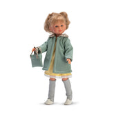 Celia doll in a green coat with stylish blonde hair, yellow dress, gray leggings, white shoes, and a matching handbag.