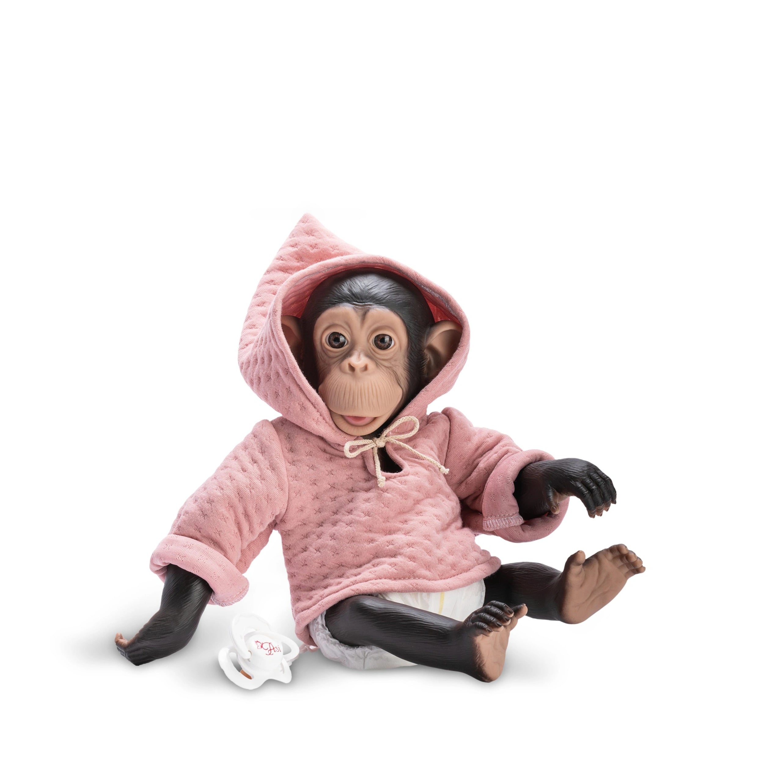 Chimpanzee doll in pink hooded dress, seated with a pacifier nearby, lifelike facial features and expressive eyes.