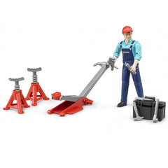 Toy mechanic figure with red cap, holding tools, stands beside red jack, jack stands, and black toolbox.