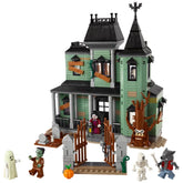 Haunted mansion constructed with green and gray bricks, featuring a detailed graveyard, spooky tree, and four character figures including a ghost, zombie, skeleton, and werewolf, along with an ornate front gate.