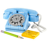 Vintage-style LEGO Creator 3in1 Retro Telephone set in soft blue, featuring a rotary dial, liftable receiver, and flexible cord, accompanied by a yellow notepad and two colorful pencils.