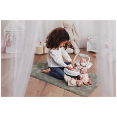 Child playing with ASI Dolls Oli Spring Collection on a cozy rug, surrounded by plush toys in a softly lit nursery.