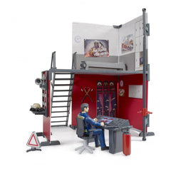 Toy firefighter figure at control panel inside the detailed Bruder bworld Fire Station playset with stairs and gear.