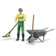 Farmer figure in yellow shirt, green overalls with a rake, standing beside a gray wheelbarrow and pitchfork.