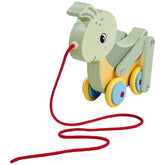Colorful pulling grasshopper toy frog with a green body, yellow belly, blue tongue, and wheels, attached to a red string.