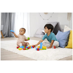 Eichhorn coloured wooden blocks are being enjoyed by two young children on a white shag rug in a bright indoor playroom.