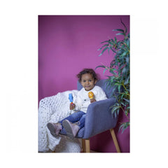 Eichhorn Maracas in a childs hands; cheerful kid in white sweater and blue jeans, smiling with colorful toys.