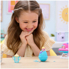 Hatchimals Alive playset with a blue egg-shaped toy and a pink toy is on the table in front of a smiling young girl.