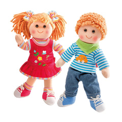 Heless Neli Soft Doll features curly orange hair, a red floral dress, blue denim pants, and red and white shoes.