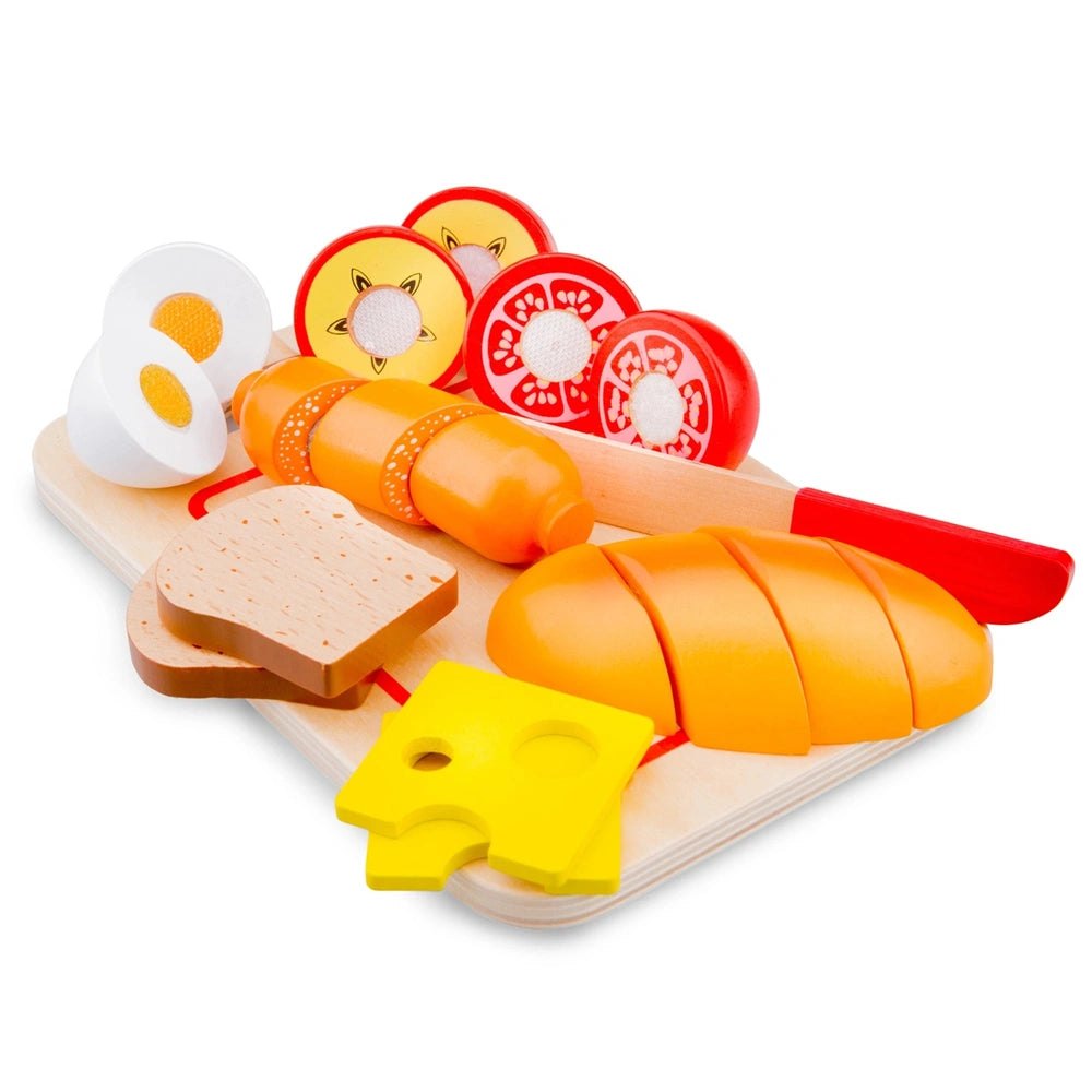 New Classic Toys cutting set featuring a wooden board, plastic eggs, bread, cheese, ham, and a red butter knife.
