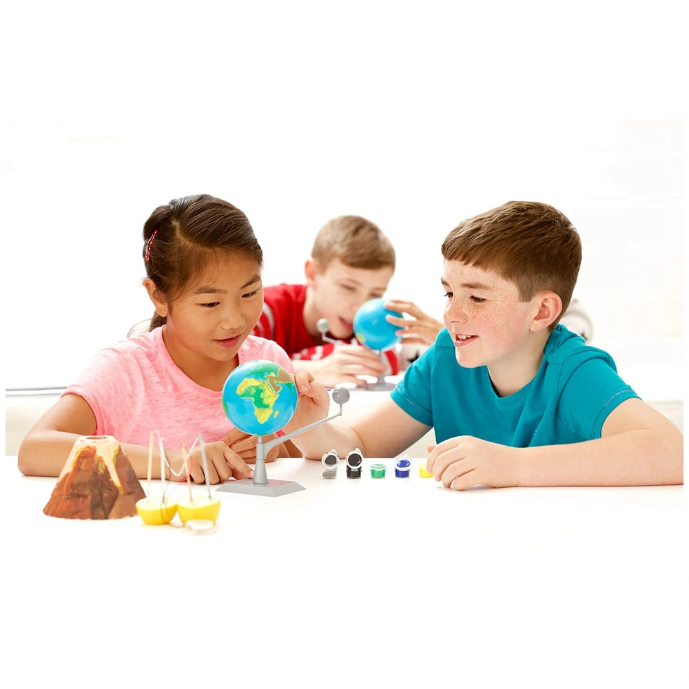 KidzLabs Earth and Moon Model Making Kit with two smiling children exploring a shiny globe on a light-colored table.