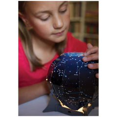 KidzLabs Night Sky Projection Kit with a girl in a red top touching a starry spherical object, eyes closed in wonder.
