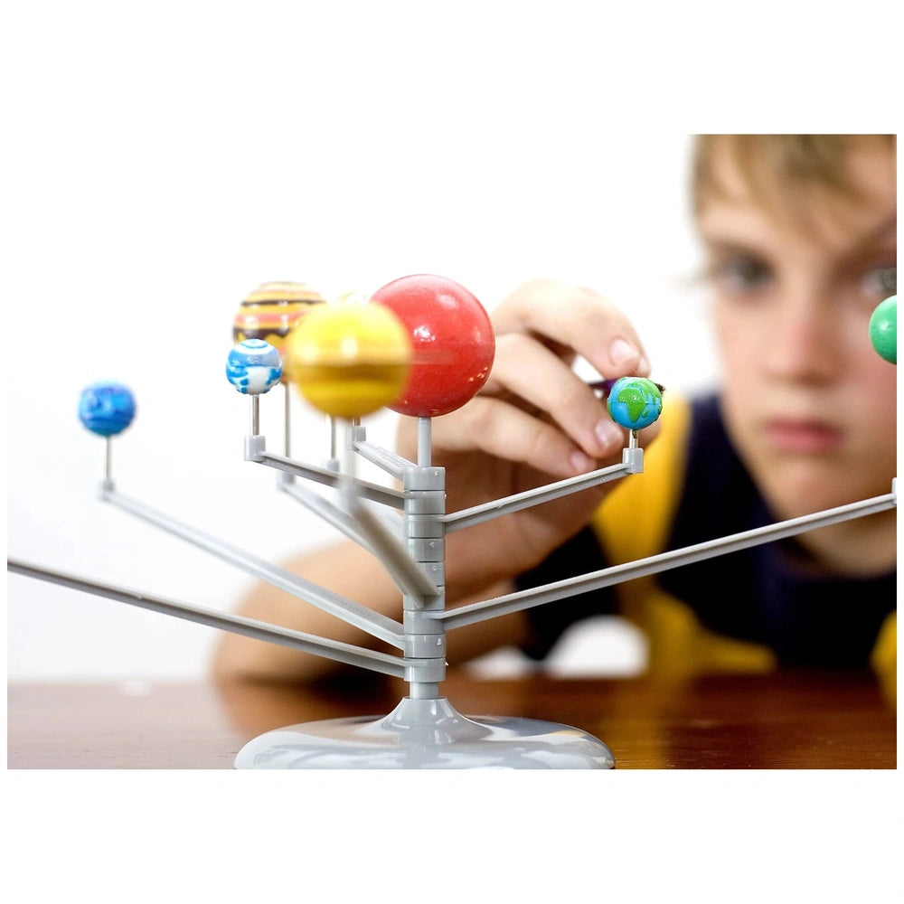 4M KidzLabs System Planetarium features a stand with four colorful spheres: red, yellow, blue, and green on a wooden table.