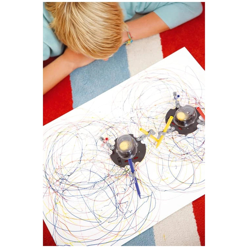 KidzRobotix Doodling Robot creating abstract lines and shapes on paper, with a person's hand guiding the robot in a close-up 