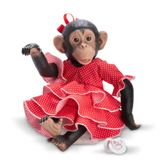 Chimpanzee doll in a red polka dot flamenco dress with a pacifier beside her, sitting playfully.