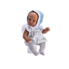Bald doll Gordi in flower dress with blue hood, seated with articulated limbs, wearing gray tights.