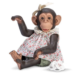 Lola the Chimpanzee doll, 32 cm, in a floral dress with a ribbon, sitting playfully.