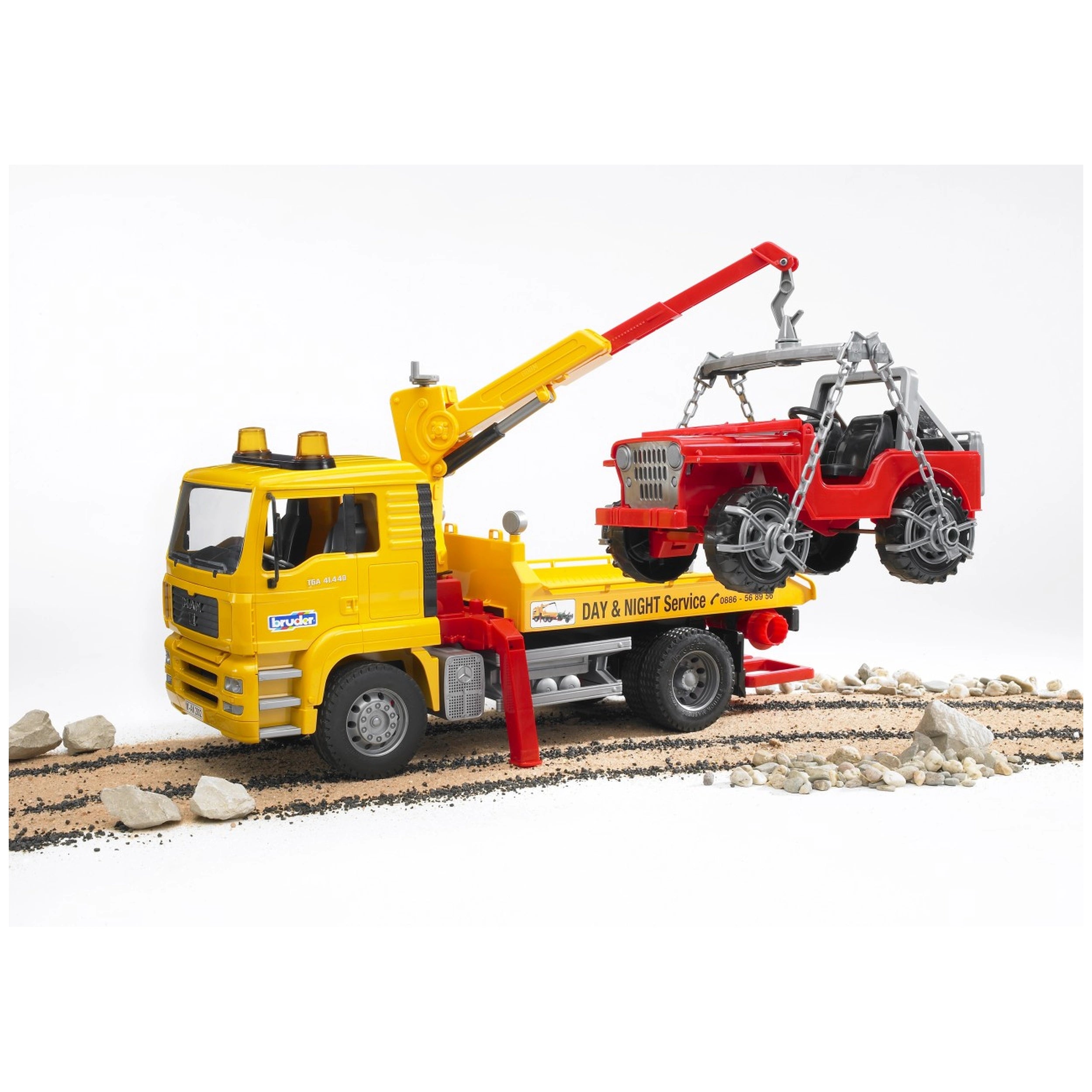 Yellow Bruder MAN TGA breakdown truck with red cross-country vehicle on the crane, set on a rocky terrain.