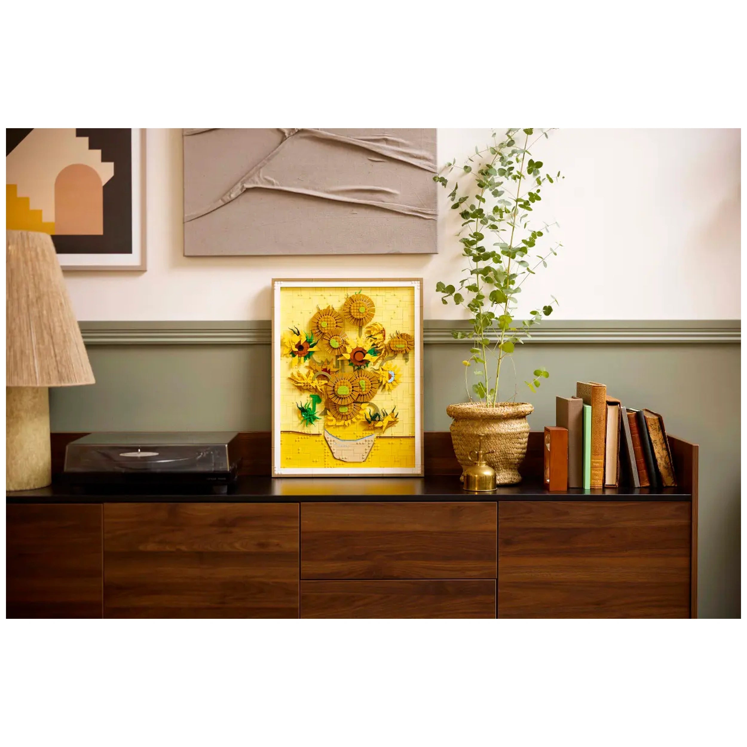 LEGO® Art Vincent van Gogh Sunflowers set displayed in a framed arrangement, featuring vibrant yellow sunflowers in a white vase, surrounded by a cozy living room setting with a record player, potted plant, and stacked books.