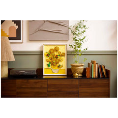 LEGO® Art Vincent van Gogh Sunflowers set displayed in a framed arrangement, featuring vibrant yellow sunflowers in a white vase, surrounded by a cozy living room setting with a record player, potted plant, and stacked books.