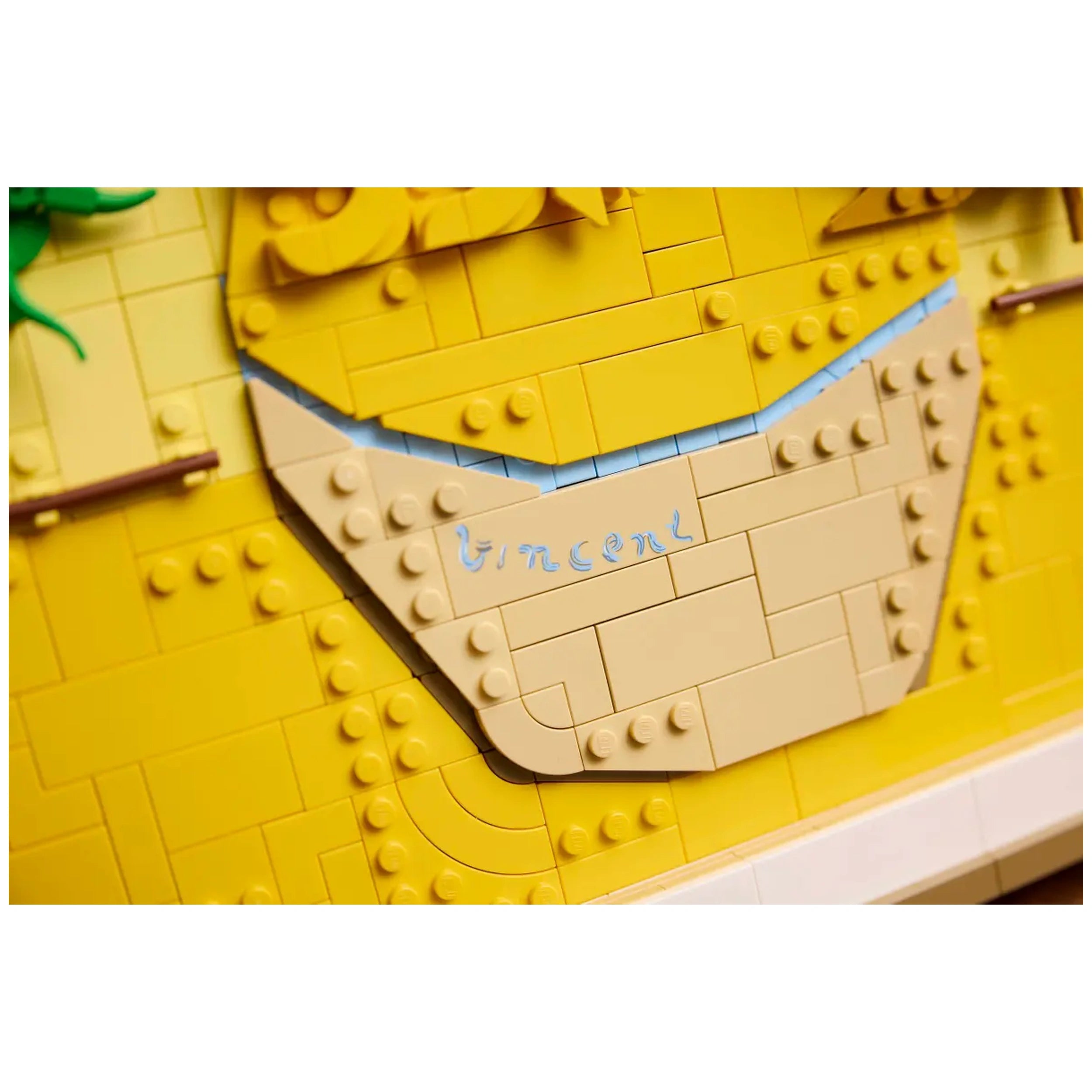 Detailed section of the LEGO® Art Vincent van Gogh Sunflowers set, showcasing a beige area with the name "Vincent" inscribed in blue, surrounded by vibrant yellow blocks representing sunflowers.