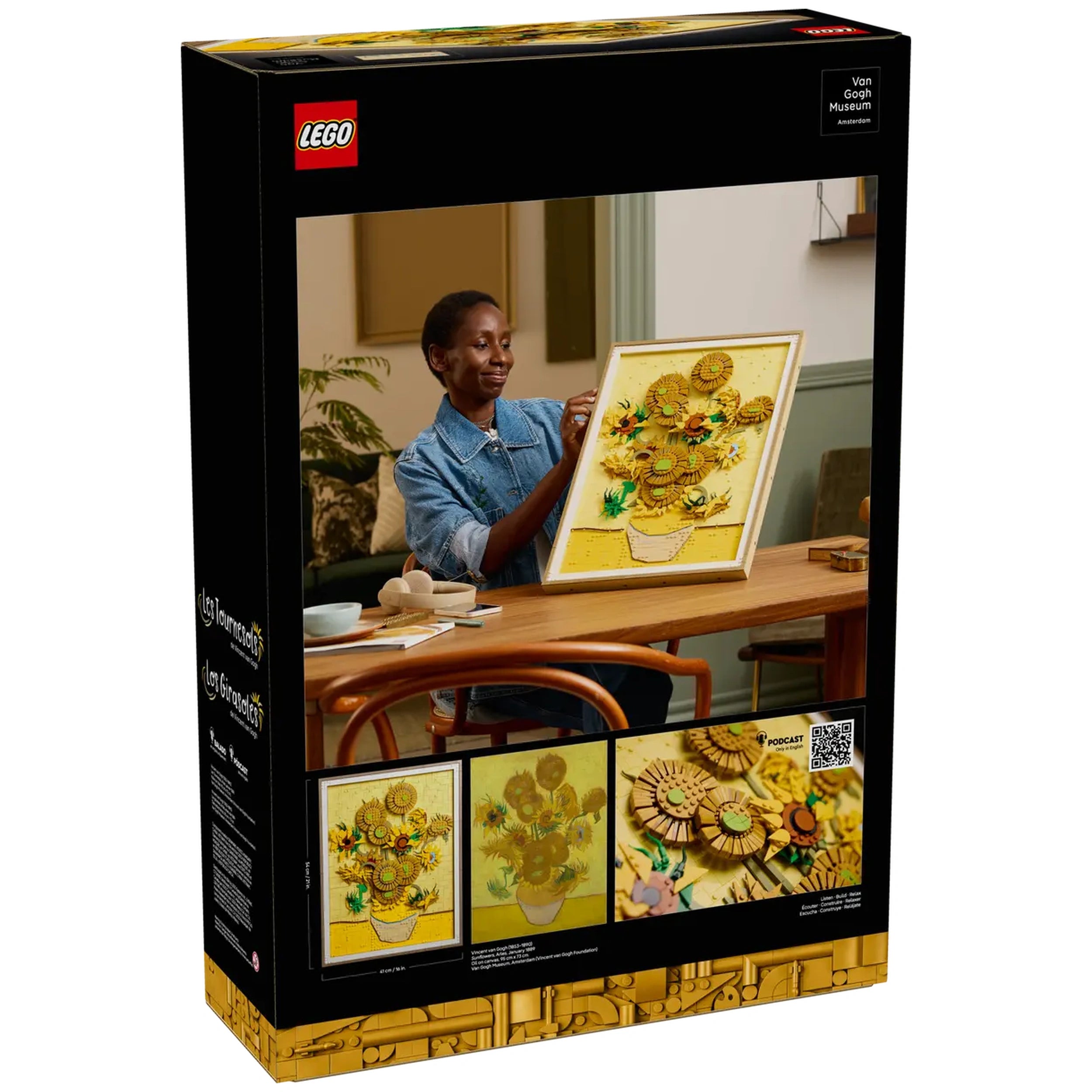 A person examines a framed LEGO® Art set featuring Van Gogh's "Sunflowers" on a table, surrounded by crafting materials in a cozy room.