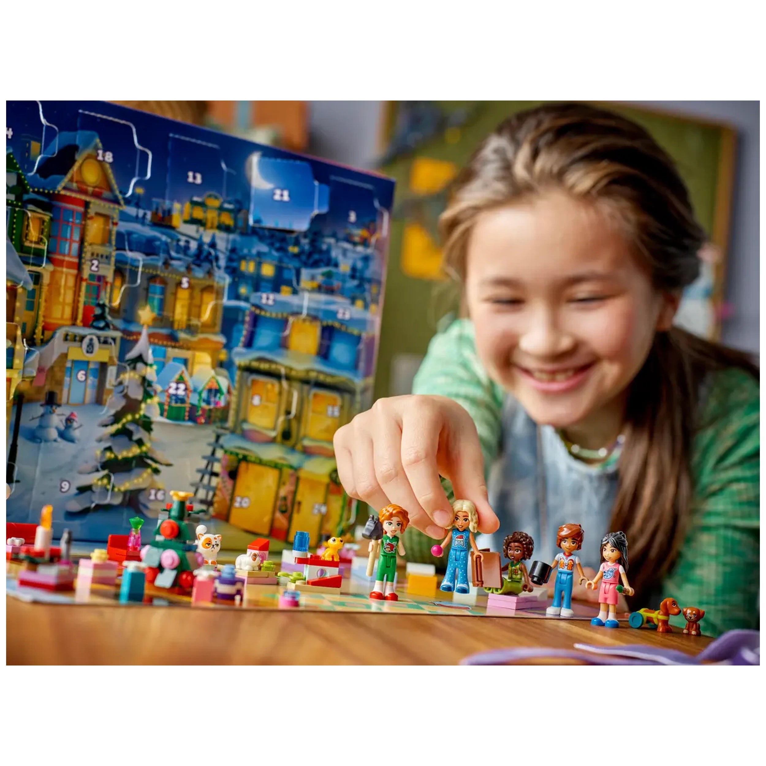A child joyfully interacts with the LEGO Friends Advent Calendar 2025, showcasing five colorful minidolls and playful accessories. The festive scene includes tiny gifts and charming LEGO animals in a vibrant setting, with a cheerful winter backdrop.