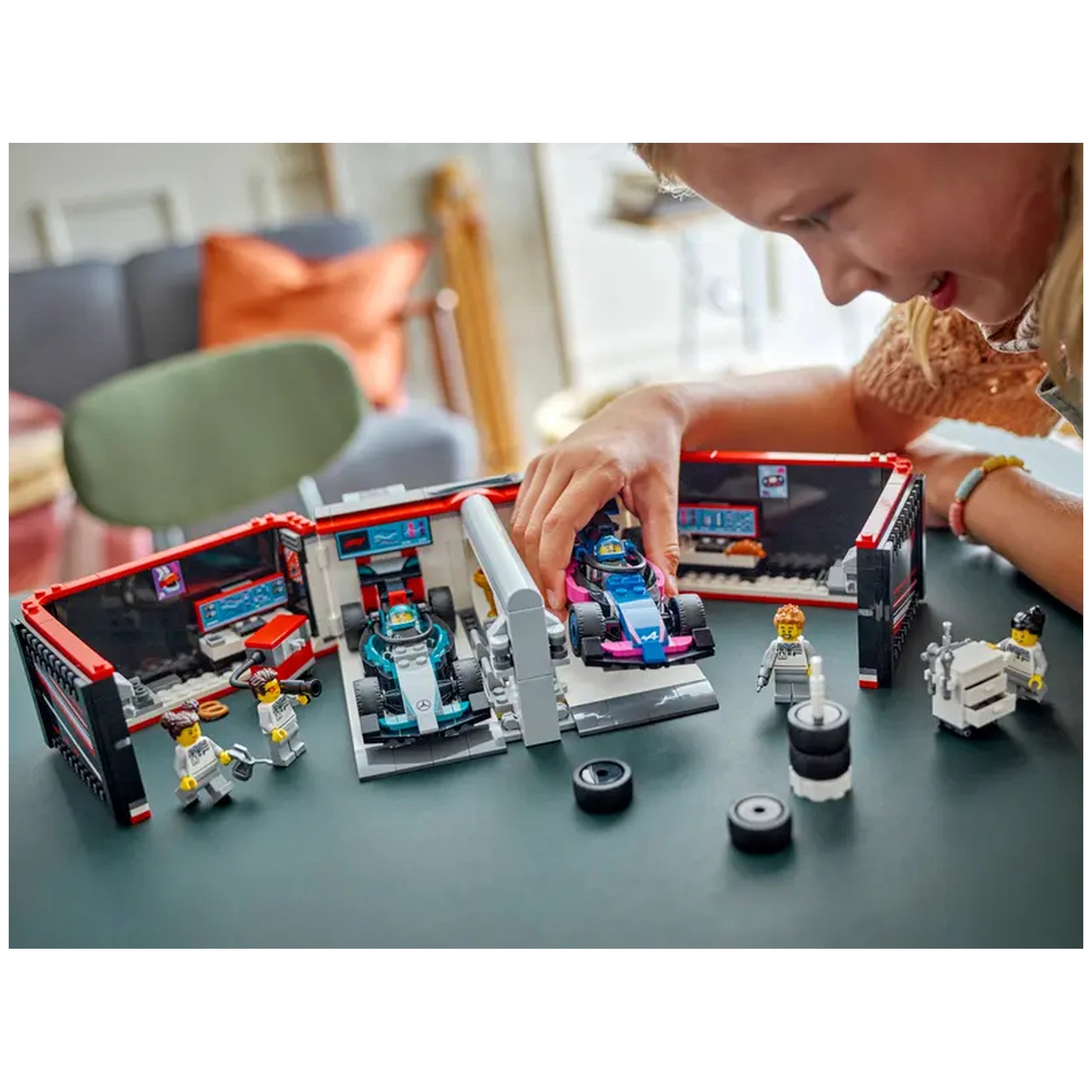 A child plays with the LEGO® City F1® Garage set, maneuvering colorful F1® race cars and interacting with tiny figures in a detailed workshop scene.
