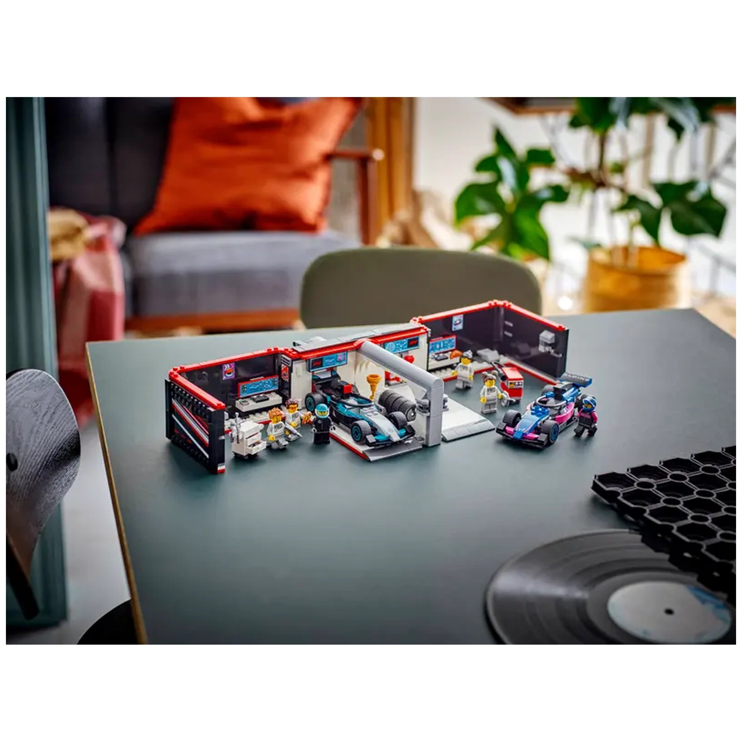 LEGO® City F1® Garage with two race cars and mechanics, featuring a detailed workshop and vibrant colors, on a tabletop.