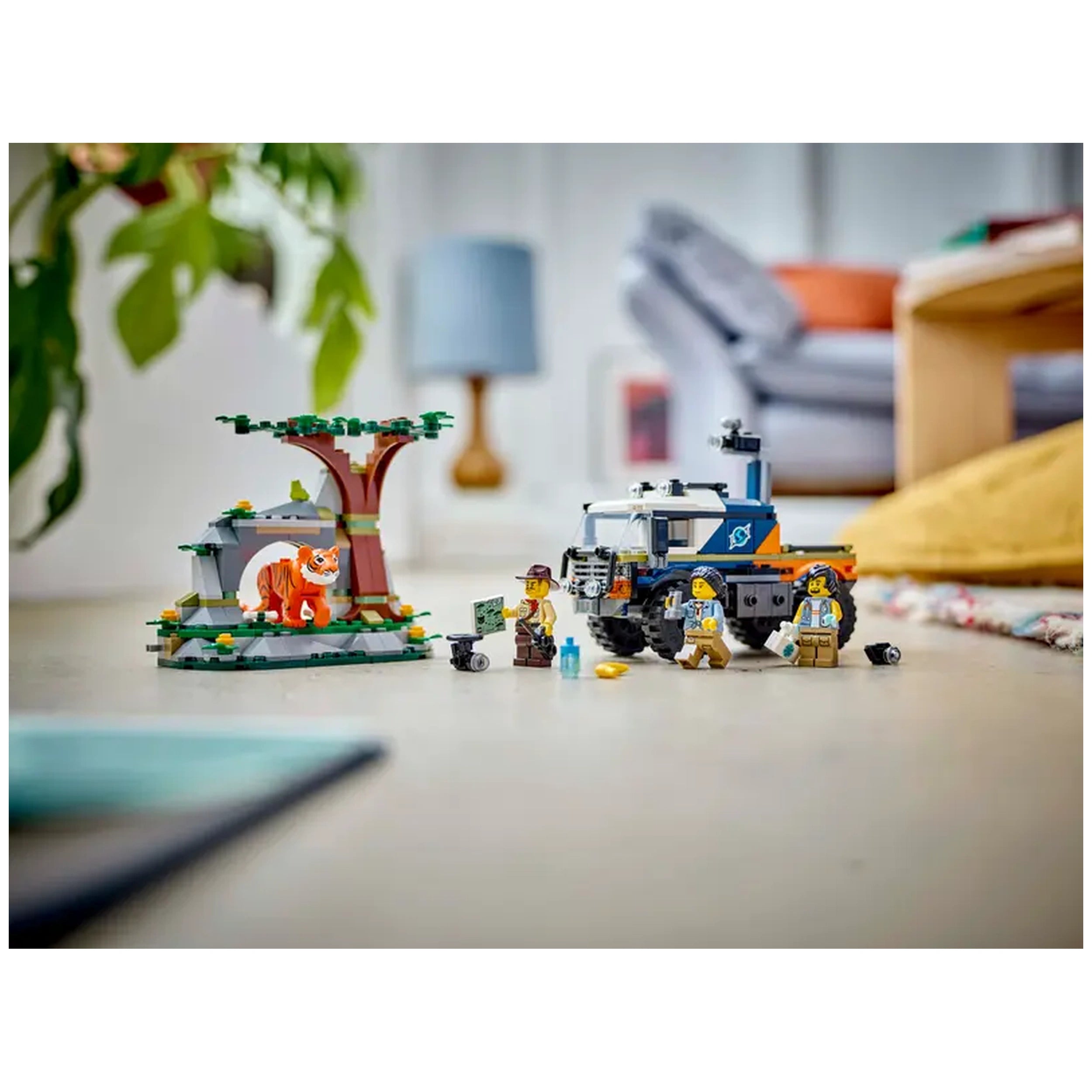 A colorful LEGO® City Jungle Explorer Off-Road Truck set featuring a rugged vehicle, three explorer minifigures, and a vibrant jungle cave with a tiger figure, all set against a home interior.