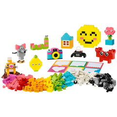 A colorful assortment of LEGO® bricks and playful elements, including animals, a camera, and a smiling emoji. Surrounding a bright, cheerful landscape, there are vibrant pieces in various shapes, inviting creativity and imaginative play.