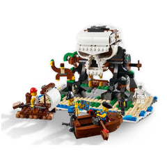 Three LEGO minifigures, a pirate captain and two crew members, interact around a colorful pirate ship and a skull-shaped rock formation. The ship features a white sail and is anchored near a sandy beach setting with tropical details. A skeleton stands nearby, and palm trees add to the adventurous scene, inviting imaginative play.