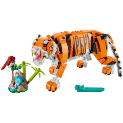 Posable LEGO® Creator Majestic Tiger in vibrant orange and black, with fierce expression, alongside a colorful red bird and a mini landscape featuring palm trees and water.
