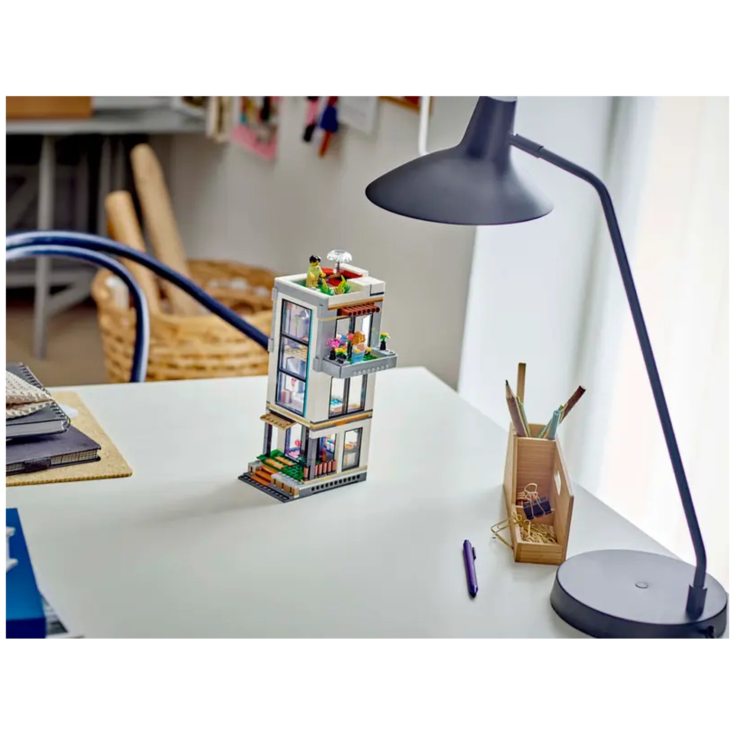 LEGO Creator Modern House construction set featuring a stylish three-story building with colorful plants and modern design elements on a desk.