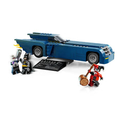 Batman and Harley Quinn minifigures stand next to the blue Batmobile, featuring detachable stud launchers and an action-packed design.