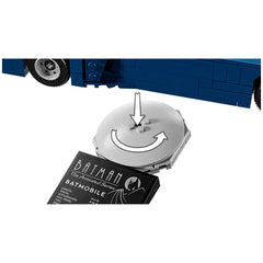 White circular piece with rotating mechanism above a black and white card labeled "Batman - The Animated Series - Batmobile," partially showing a blue toy vehicle's wheel to the side.