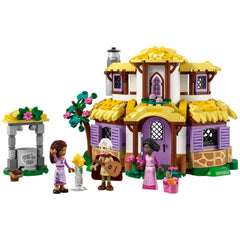 A colorful LEGO® construction set featuring Asha's Cottage, with a two-level house, a well, and three characters, each holding accessories.