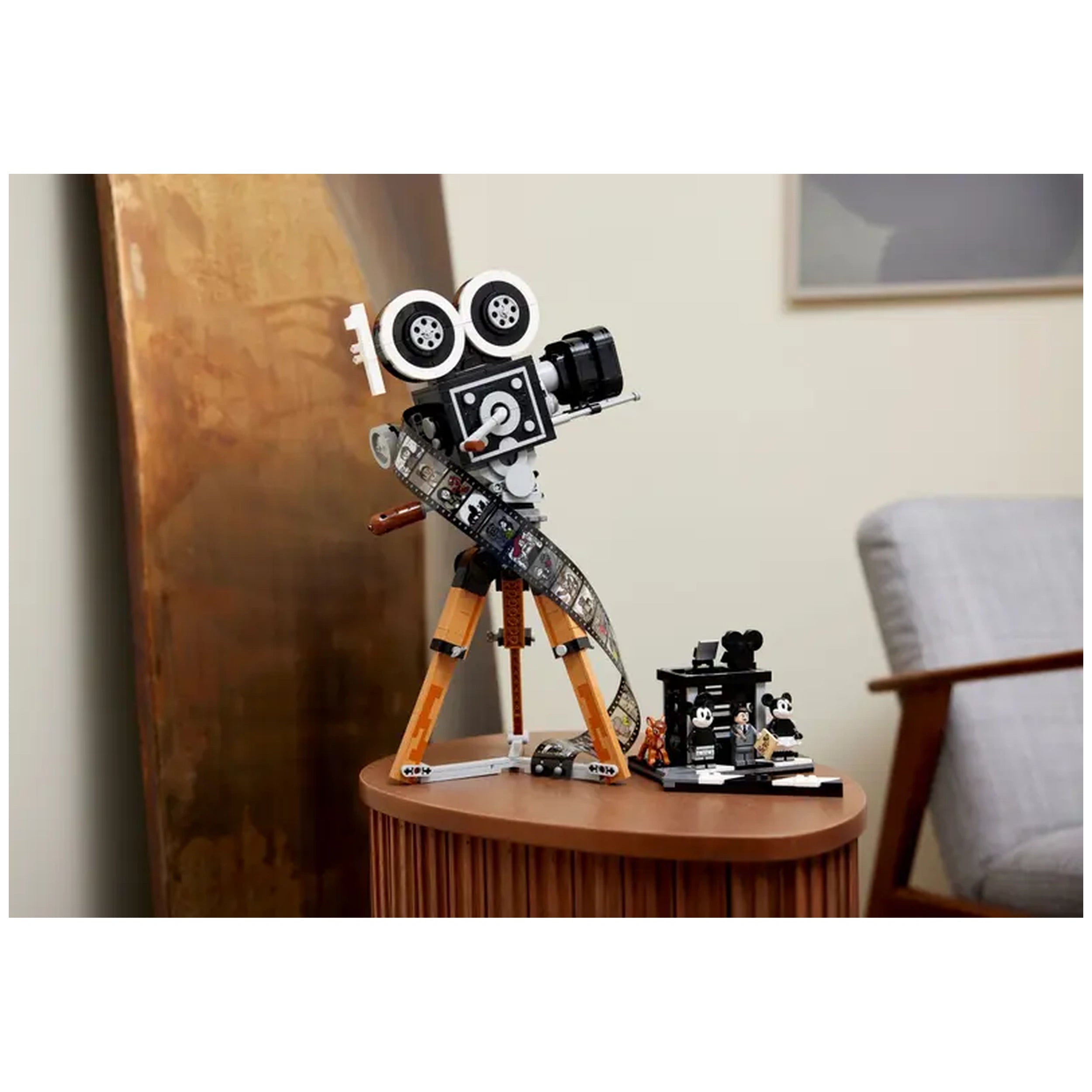 Vintage-style LEGO® Disney camera on a wooden table, featuring a film strip and a director's clapperboard with minifigures.