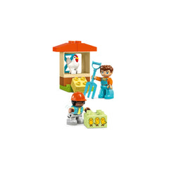 Two playful children engaged in a farm scene with a chicken coop, a chicken inside, and a block depicting three chicks. One child holds a pitchfork, while the other is playing with animal blocks, both wearing colorful outfits.