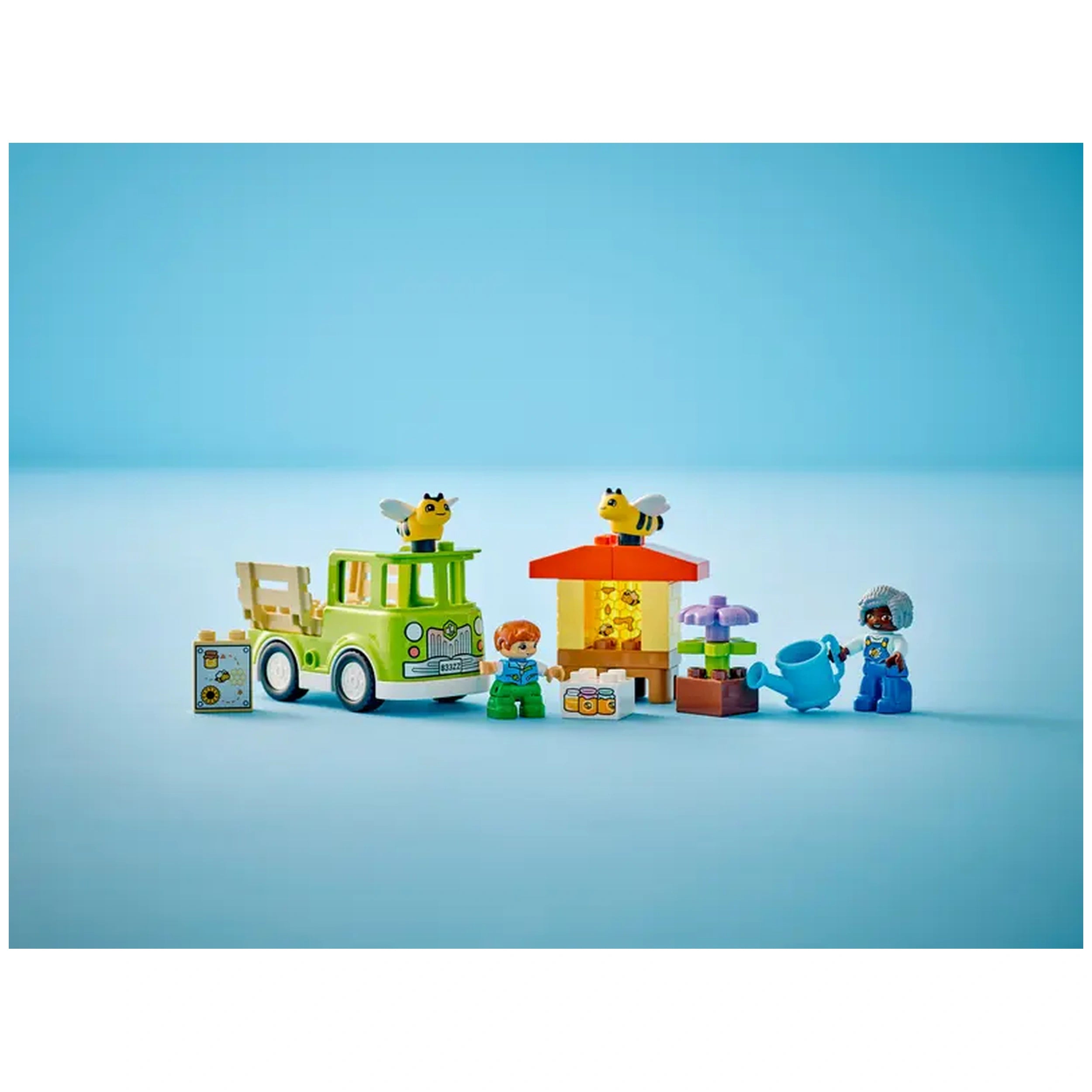 Colorful LEGO® DUPLO® Caring for Bees & Beehives set features a green toy truck, a beehive, two bees, and playful figures, encouraging creative nature exploration.
