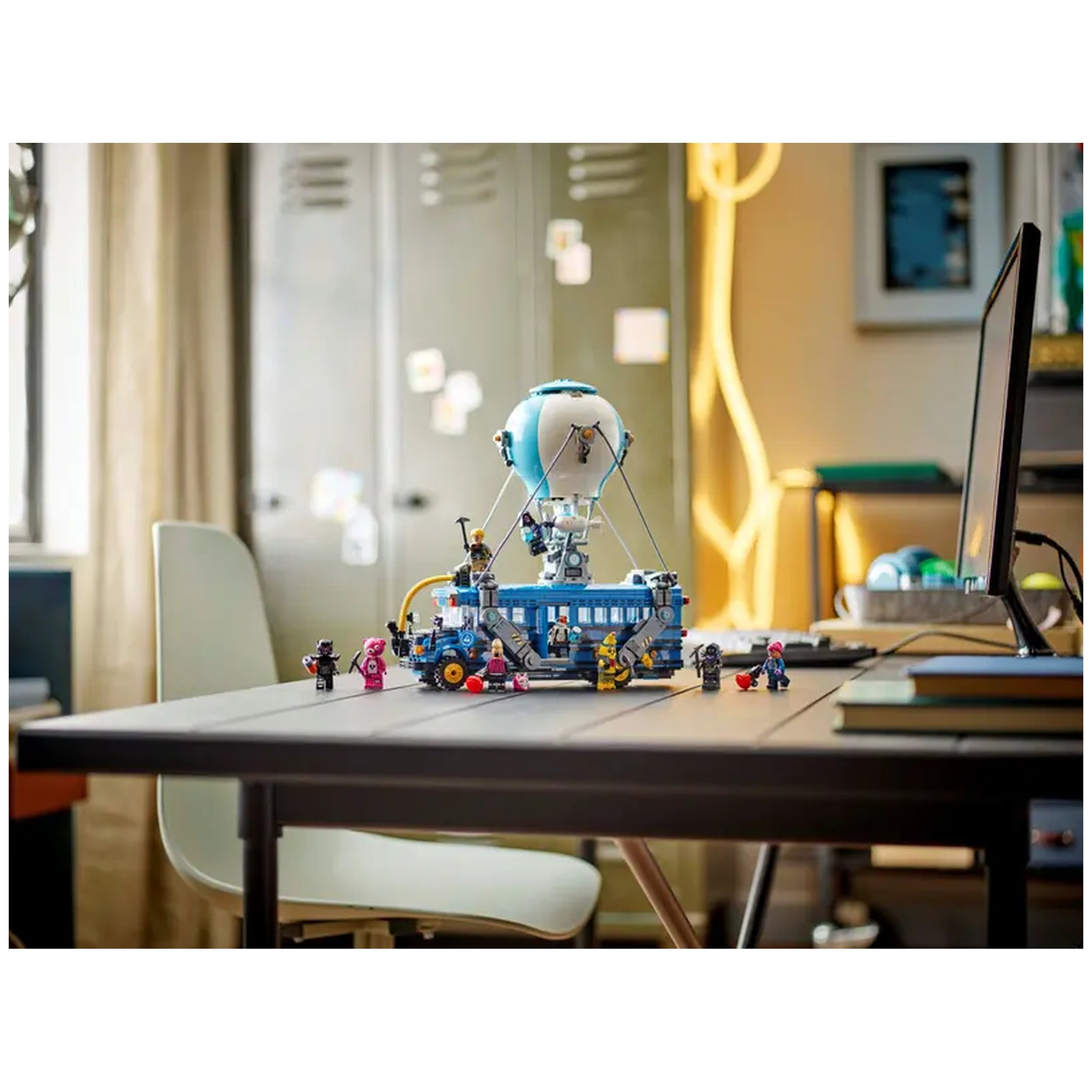 LEGO Fortnite Battle Bus construction set displayed on a table, featuring a colorful hot-air balloon and various character figures around it.