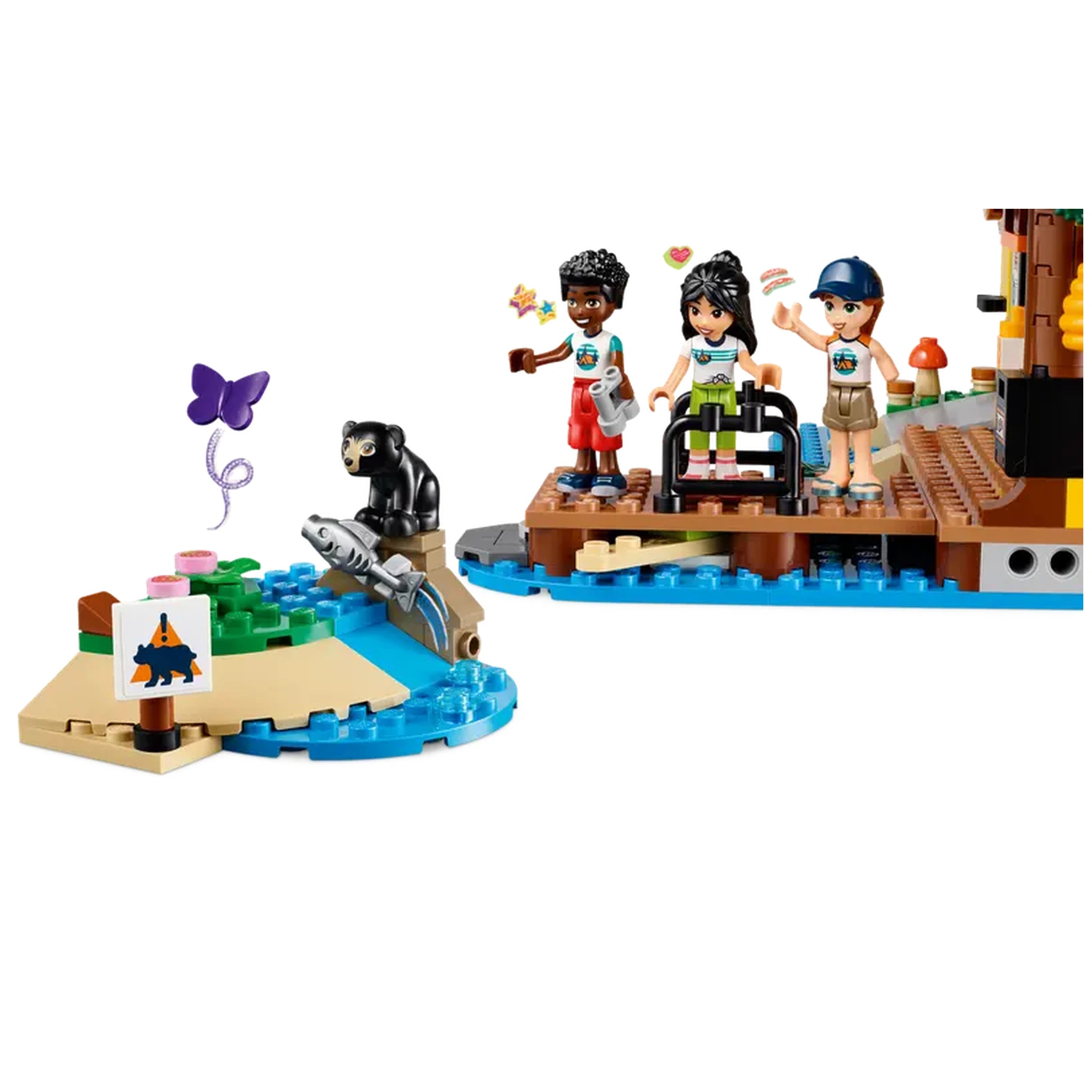 Three LEGO Friends mini-dolls, Autumn, Liann, and Zac, stand on a colorful dock with a bear figure nearby. A small island features water sports accessories, including a fishing rod and unique animal signs. Vibrant scenery invites imaginative outdoor play.