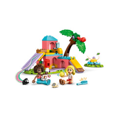 Two LEGO Friends minidolls sit with guinea pigs beside a colorful playground, featuring a slide and tree, inviting imaginative play.