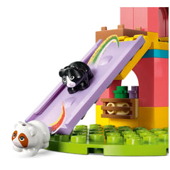 Two cute guinea pig figures sliding down a colorful purple slide in a vibrant LEGO playground with green grass elements.