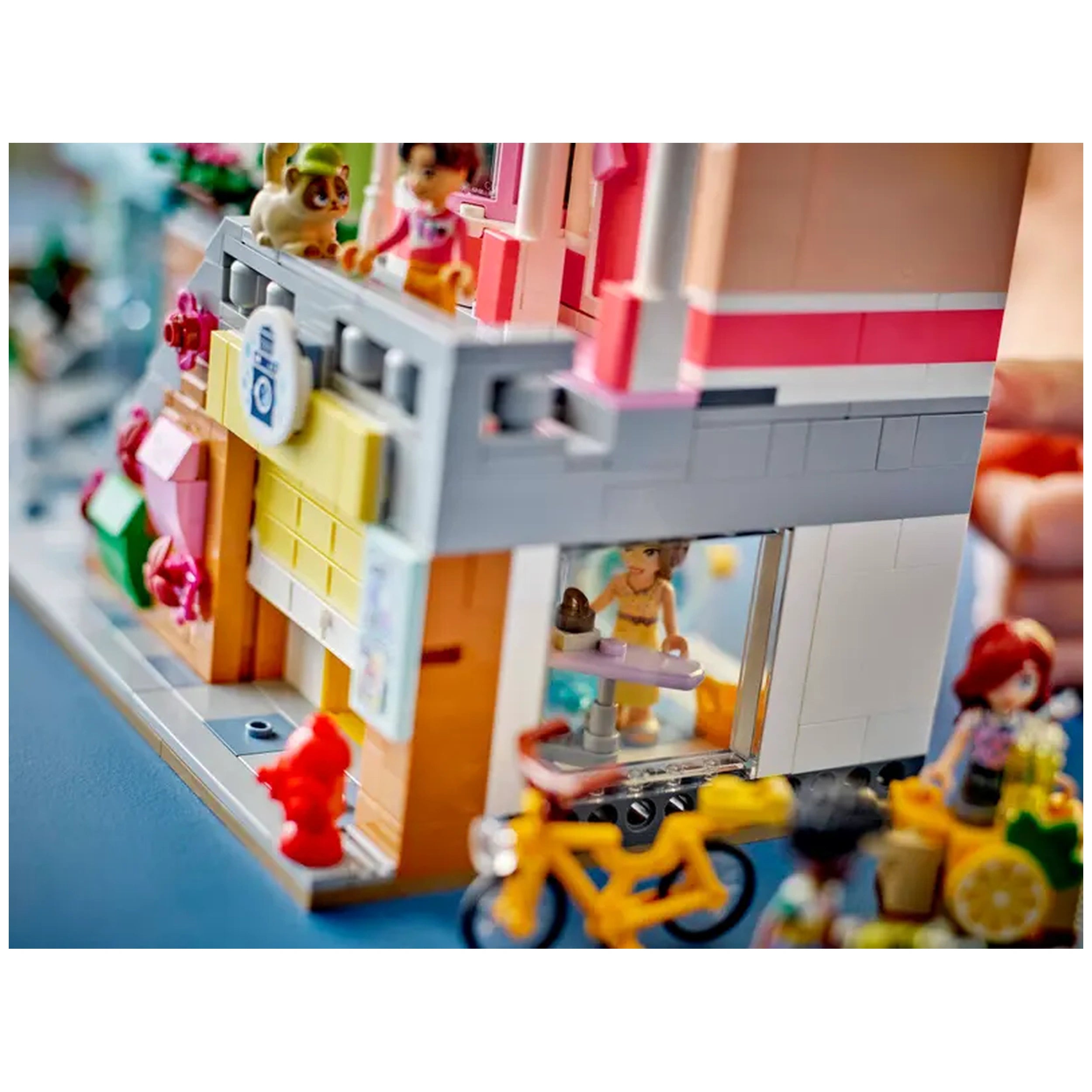 Colorful LEGO Friends Heartlake City Apartments, featuring a character serving treats from a bakery, with a bicycle and friends nearby.