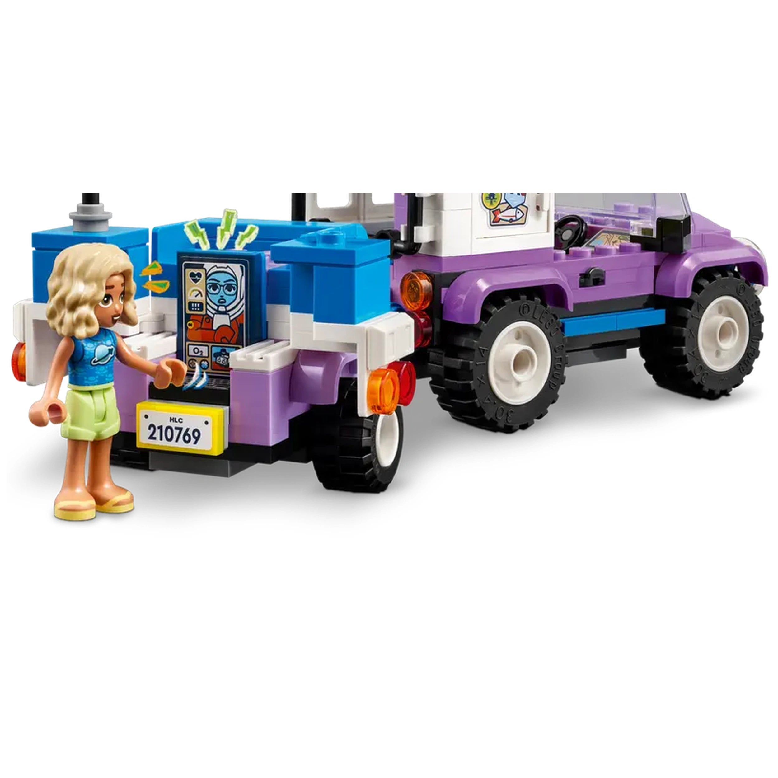 A LEGO® Friends mini-doll stands beside a colorful stargazing camping vehicle, displaying tools and designs on the back.