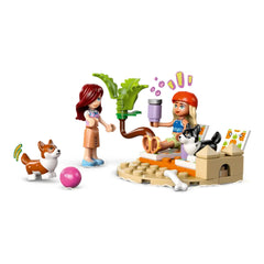 Two LEGO Friends minidolls enjoy beach lounging near a palm tree, with playful corgis and accessories like a pink ball.