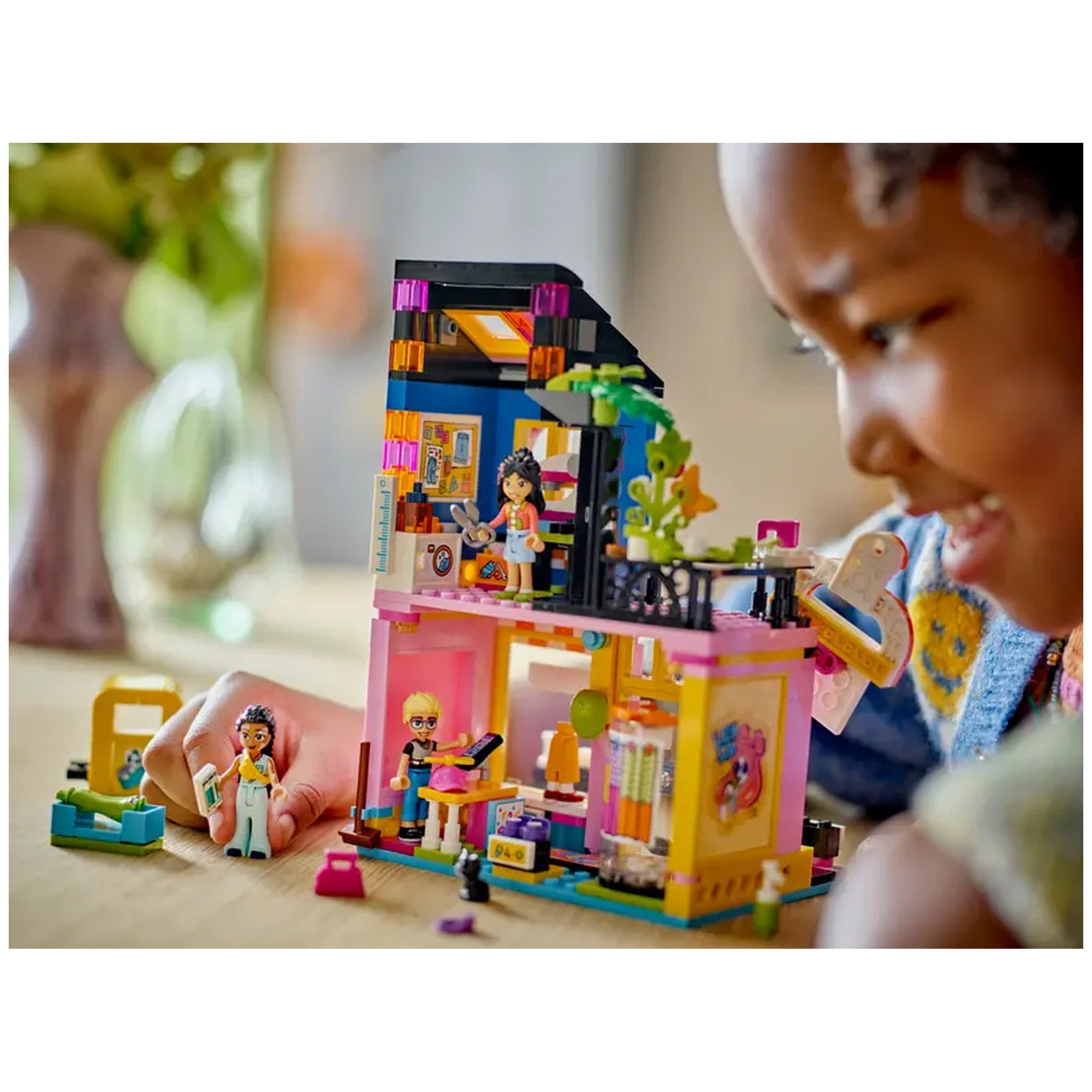 LEGO® Friends Vintage Fashion Store set with colorful building, three characters, and accessories, enjoyed by a smiling child.