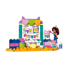 A colorful LEGO® Crafting with Baby Box set featuring a Gabby mini-doll figure painting a vibrant wall. There are crafting supplies like paint, scissors, and a pink Baby Box figure, with a whimsical background decorated with drawings and playful elements.