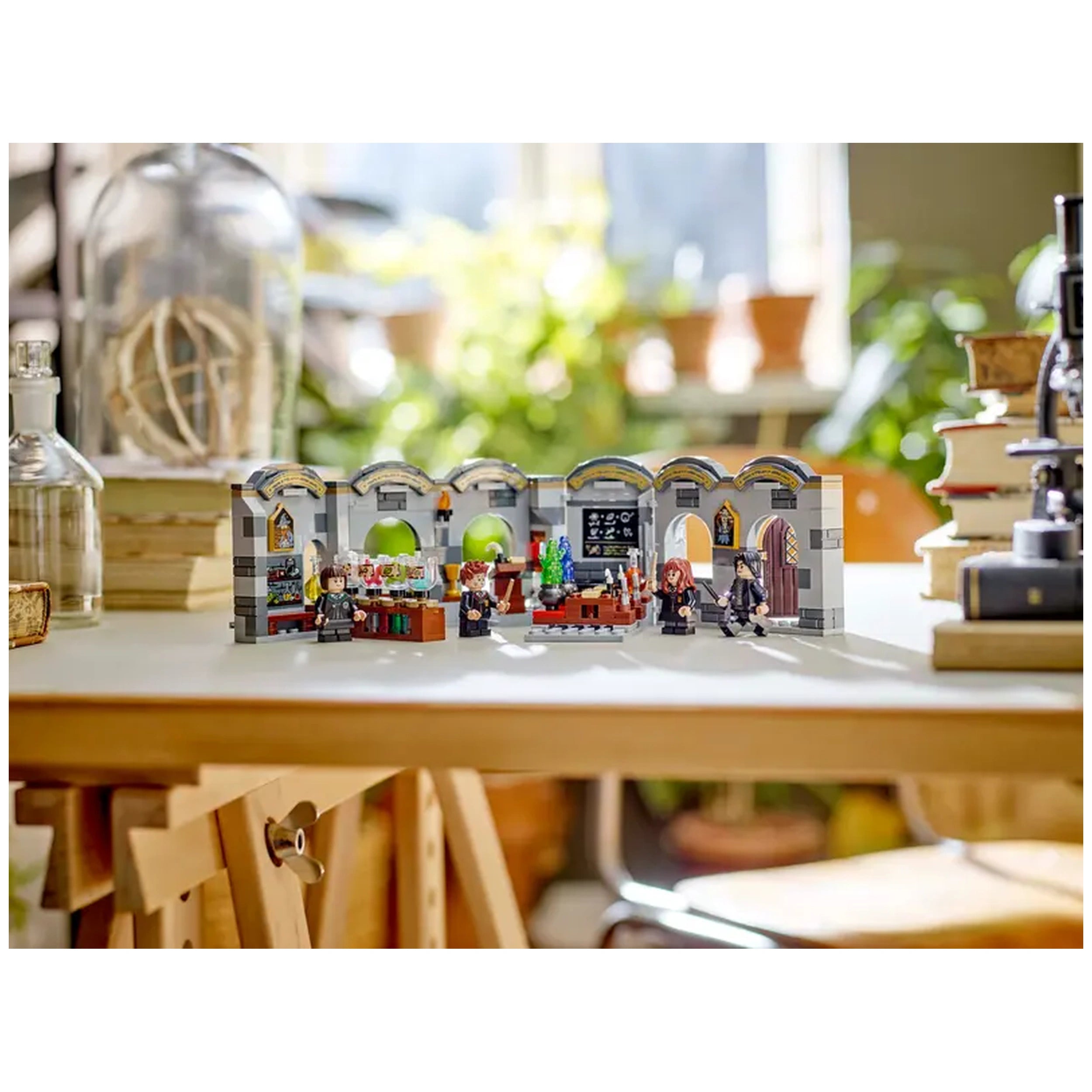 LEGO® Harry Potter™ Hogwarts Castle: Potions Class set on a bright table, featuring minifigures of Hermione Granger, Severus Snape, and Pansy Parkinson, surrounded by potion ingredients and a blackboard.